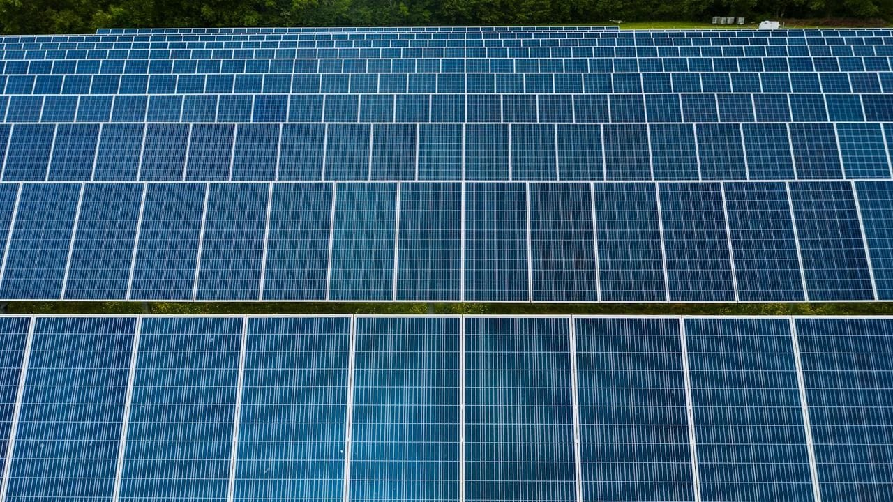 Solar panels installed in a field under a clear blue sky.