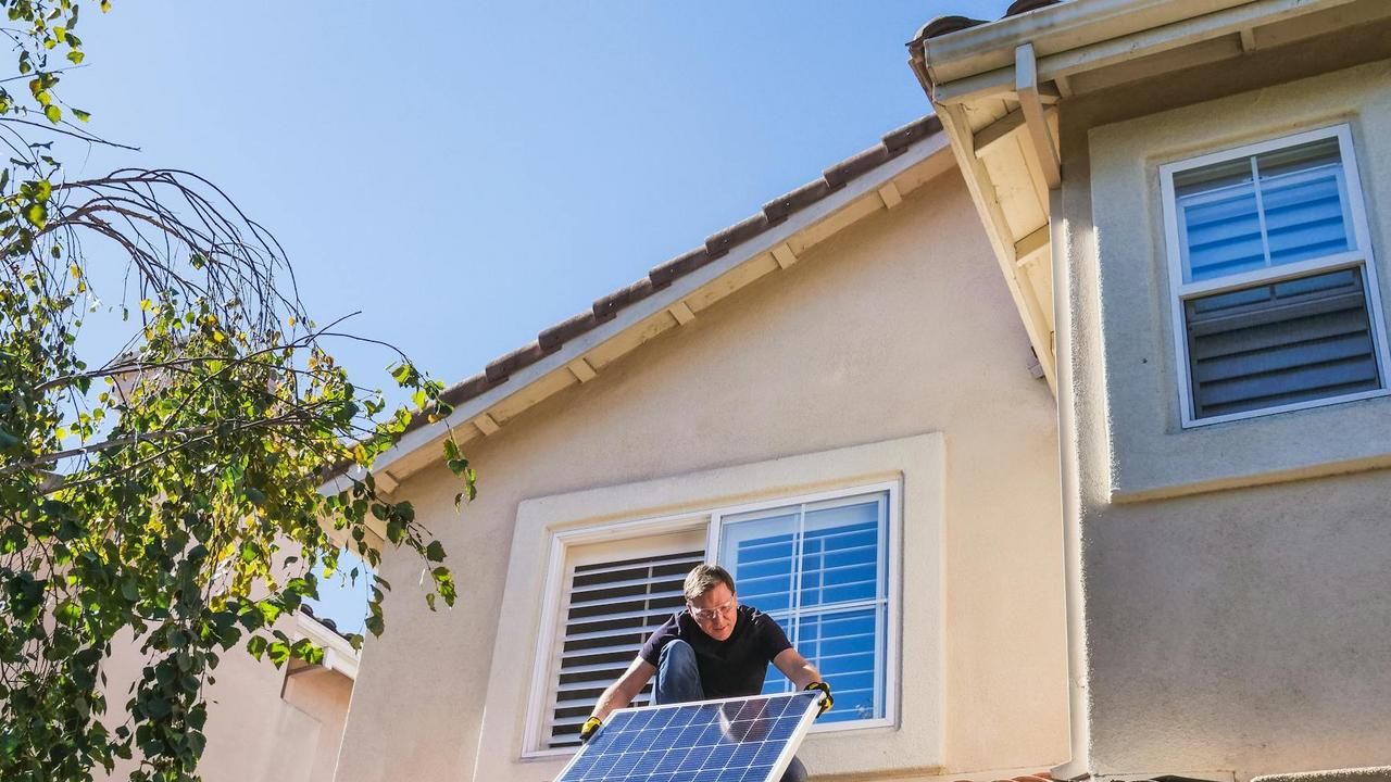 A technician performing solar panel maintenance on a roof.