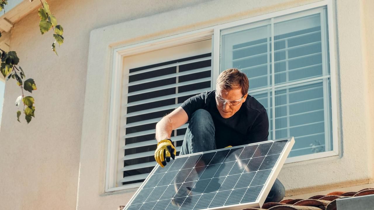 A technician in gloves installing or maintaining solar panels on a roof.