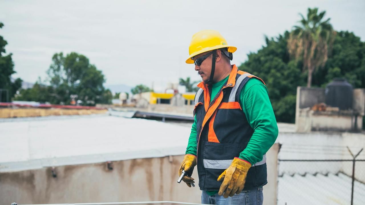 A professional solar technician in safety gear inspecting solar panels on a rooftop.